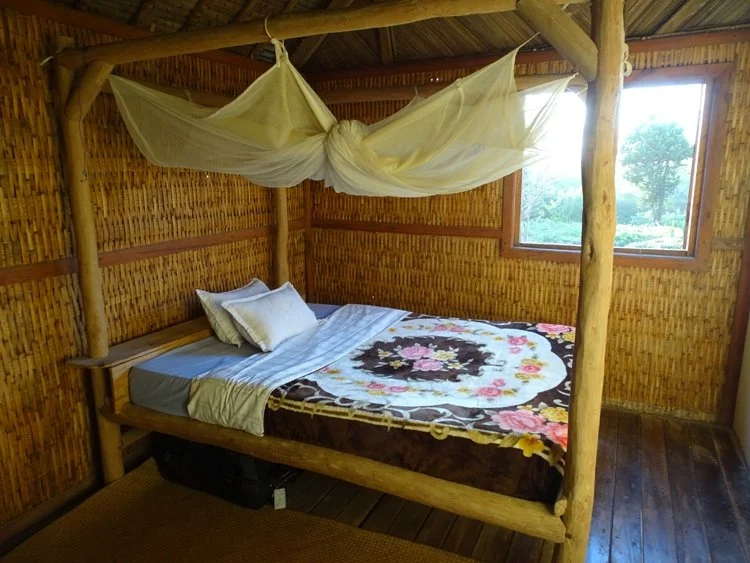 A mosquito net hands over a floral bed with bamboo walls in Belize.