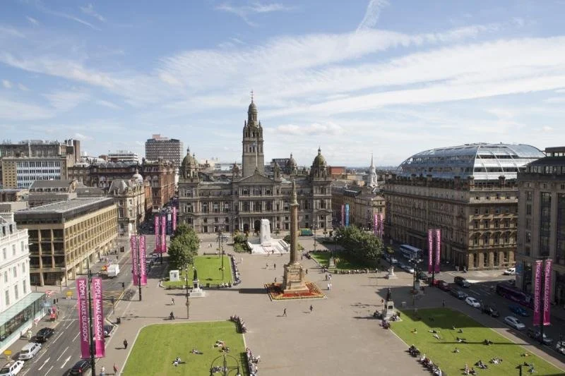 A panoramic view of four grass patches a George Square in Glasgow.