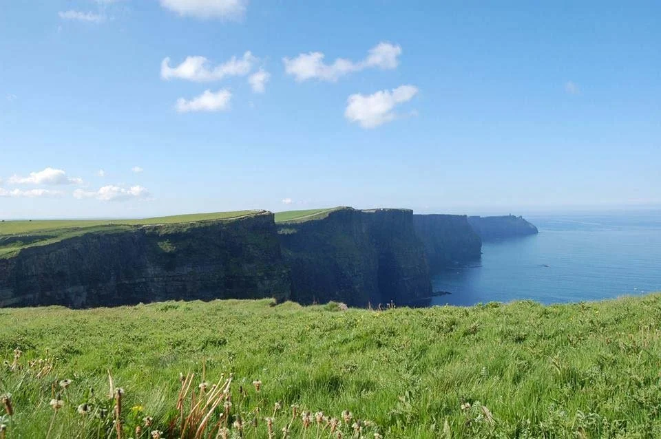 The Cliffs of Moher tower over the ocean during a clear day.