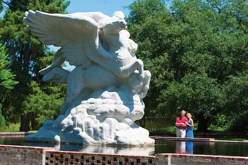 A couple looks at a statue of a white pegasus at Brookgreen Gardens.
