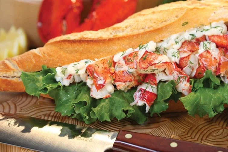 Chunks of lobsters ooze out of a lobster roll.