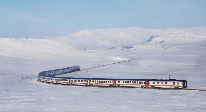 A train weaves its way through a snow covered mountain range in Turkiye.