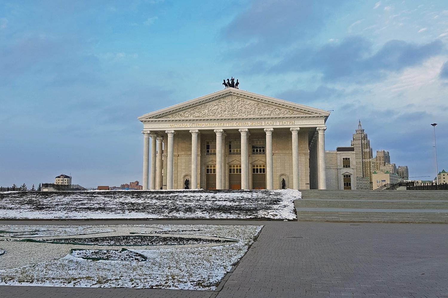 White columns with small horses on top of the roof of the Astana Opera.