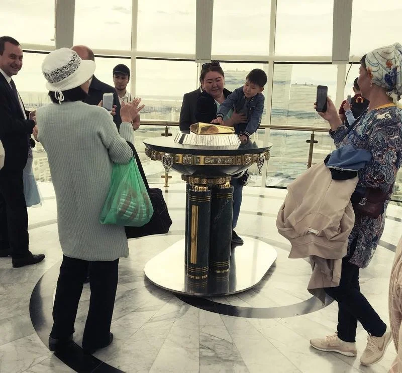 A woman holds a child above a handprint of President Nazarbayev.