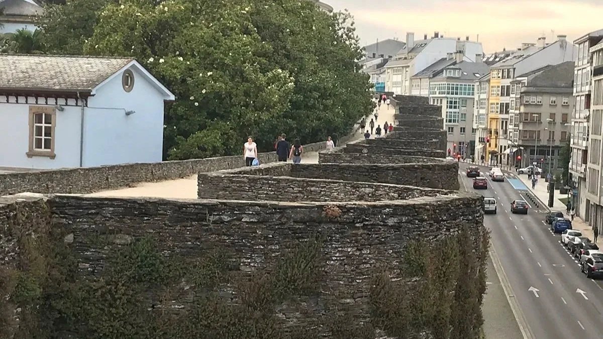Walkers make their way up the ancient city walls of Lugo during sunset.
