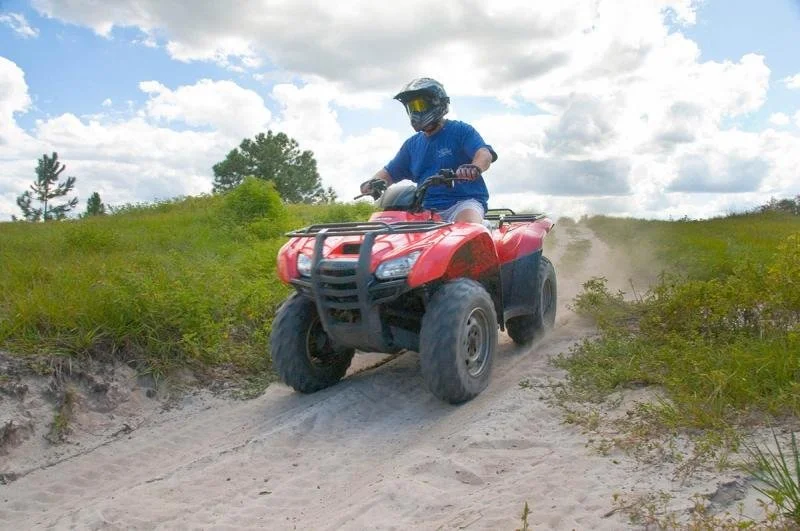 A man drives over the sand on an ATV from Revolution Adventures ATV course.
