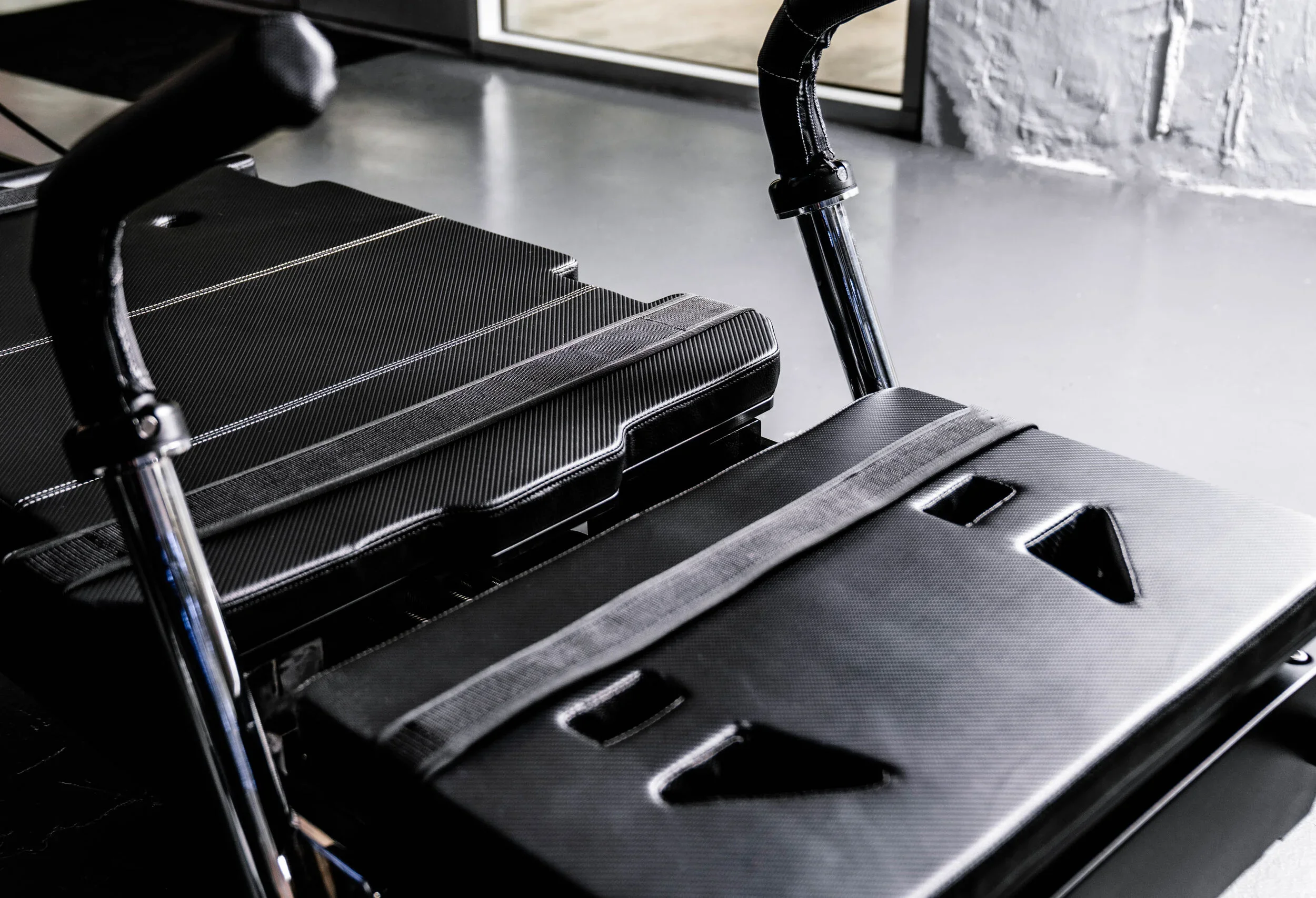 Close-up of a modern reformer, black textured surfaces and silver metal frame parts, positioned indoors near a window.