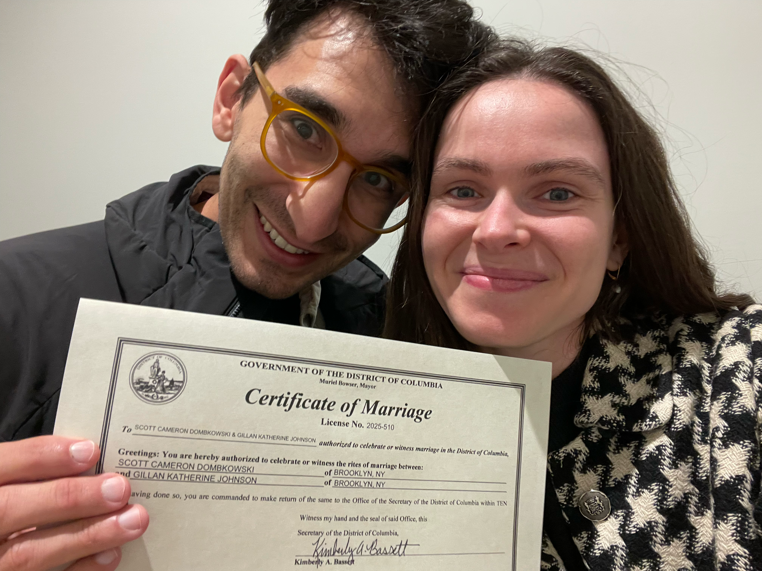 A man and woman smiling and holding a marriage certificate from the District of Columbia.