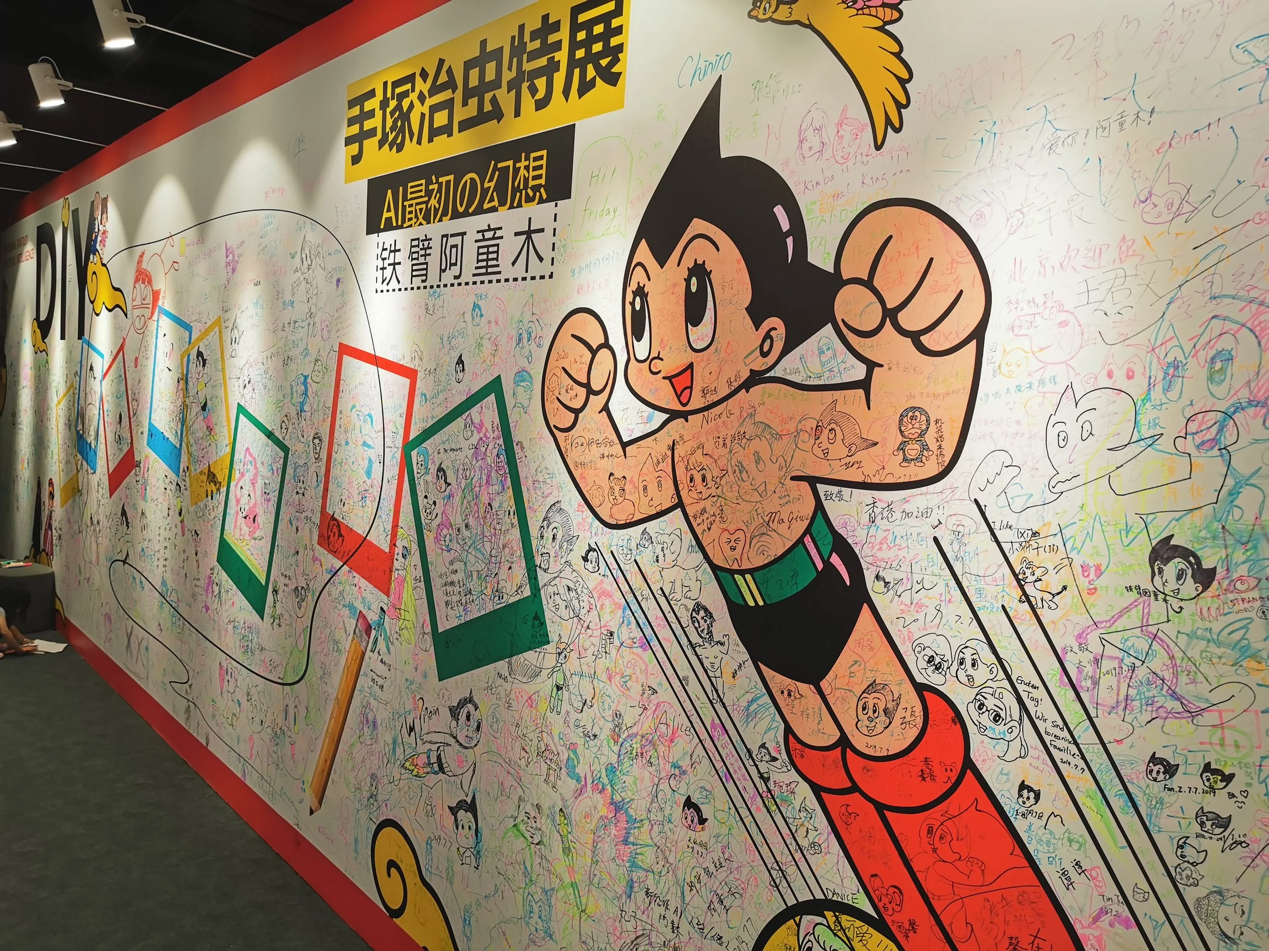 Colorful wall with a large cartoon of Astro Boy, signed with drawings and messages from visitors.
