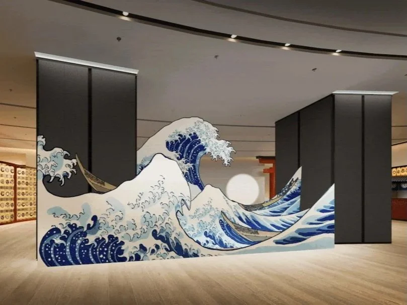 Large mural of Mount Fuji and ocean waves inspired by Hokusai, inside a modern building lobby.