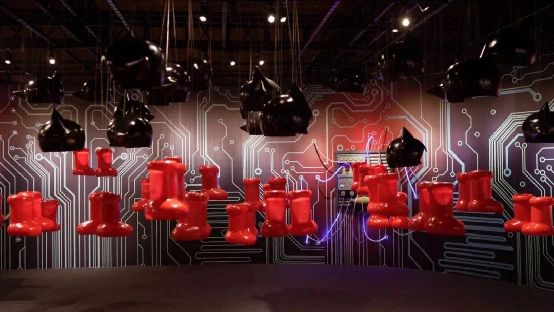 A room with red chairs hanging upside down from the ceiling, black headphones hanging above, and a background of circuit board patterns with neon lights and electronic equipment.