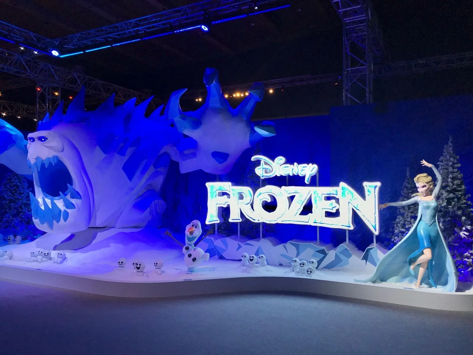 Frozen-themed display with a large white dragon head, a snowman character, and Elsa in a blue dress, with a sign that says Disney Frozen.
