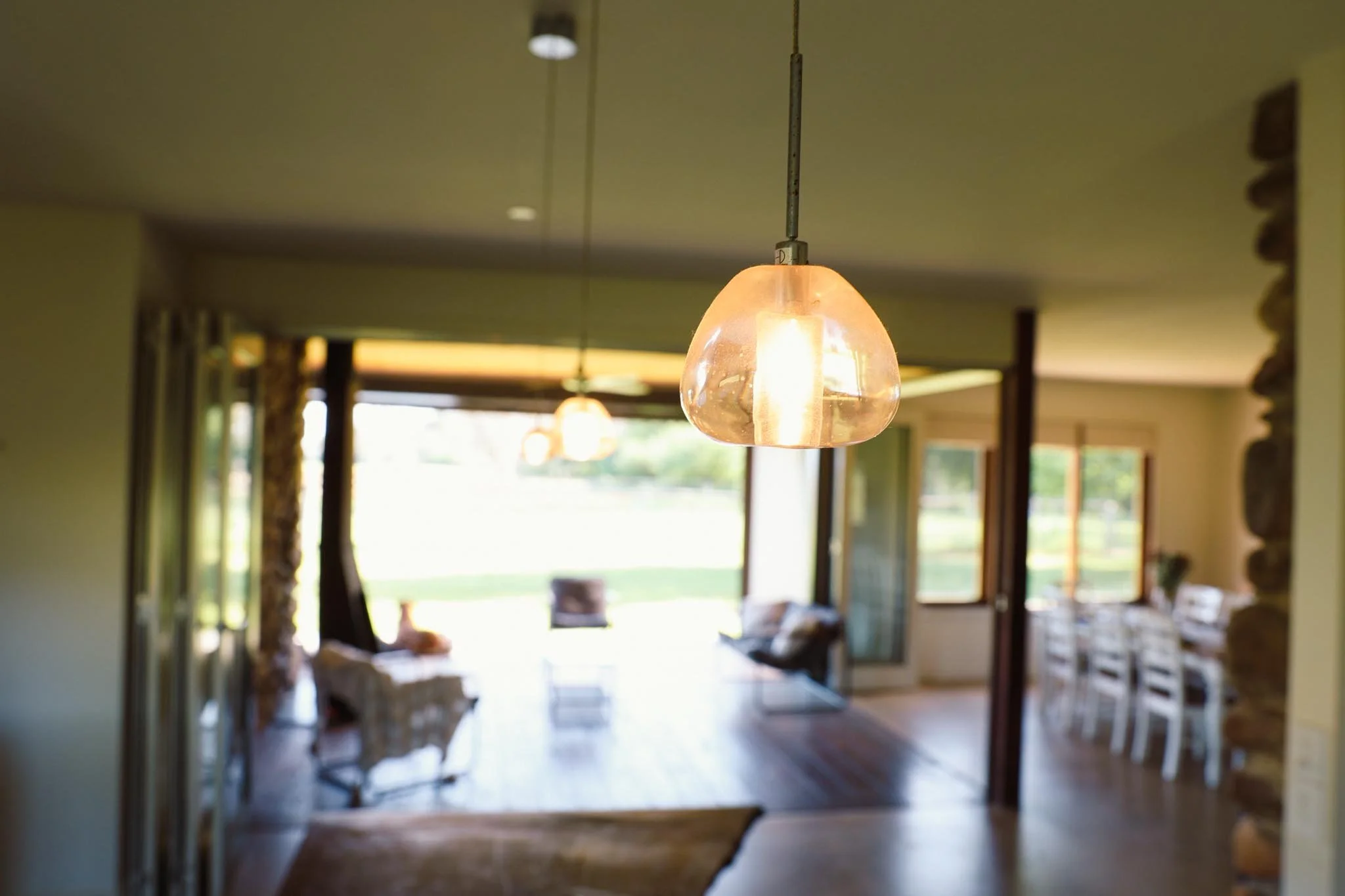 Pendant light with a glass shade hanging from the ceiling in a bright living room.