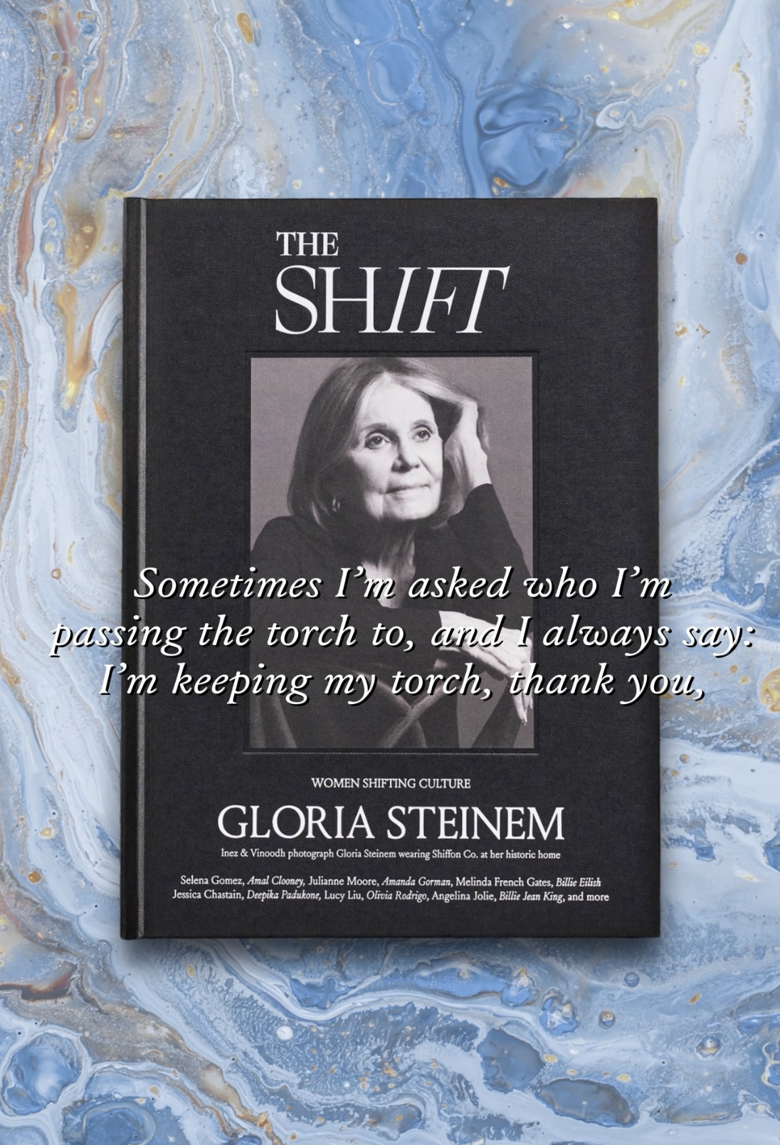 A book titled "The Shift" featuring Gloria Steinem on the cover, placed on a blue and gold marbled background.