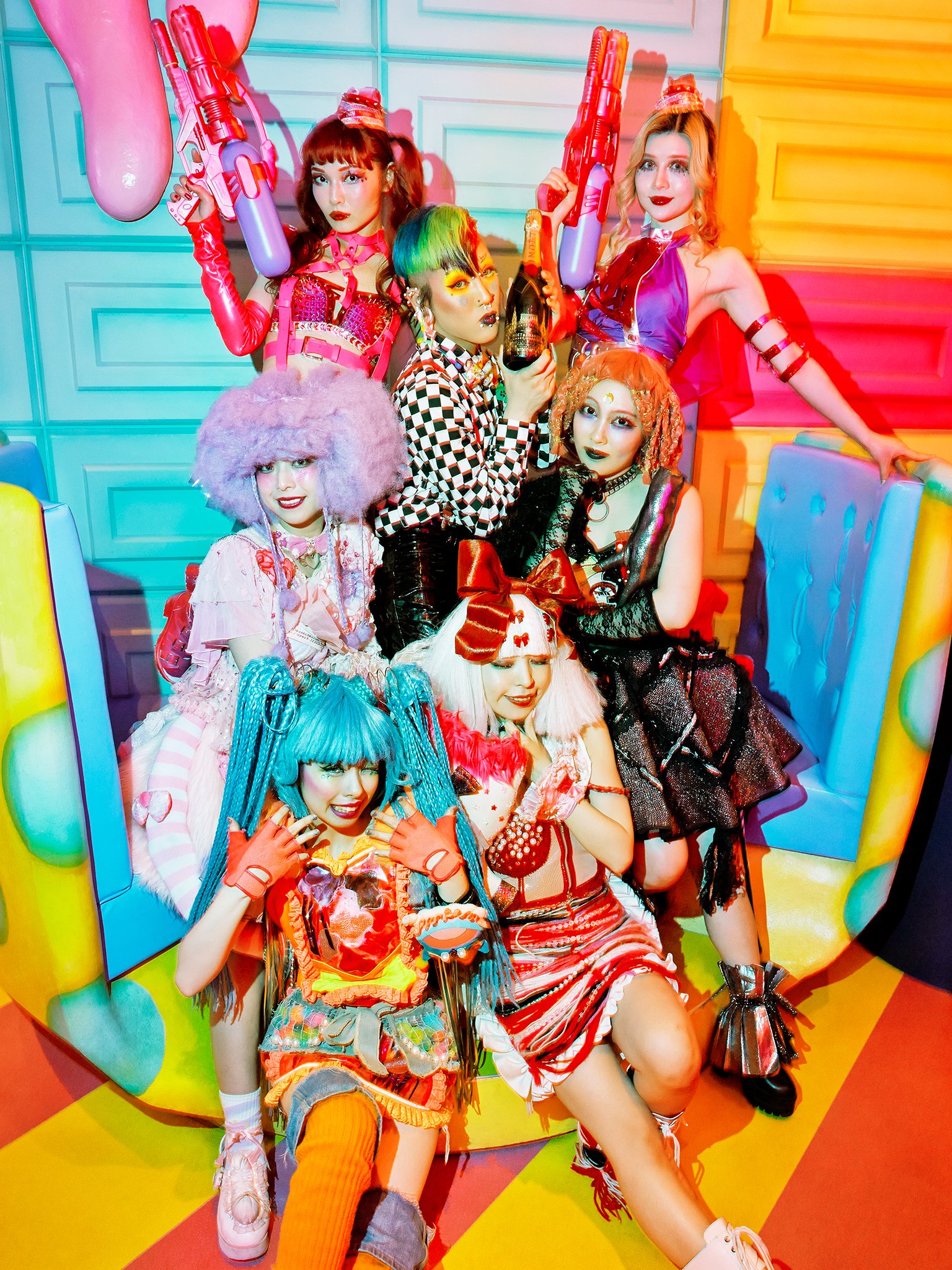 Group of women with colorful and punk fashion styles posing together against a vibrant, playful background with bright colors and patterns.