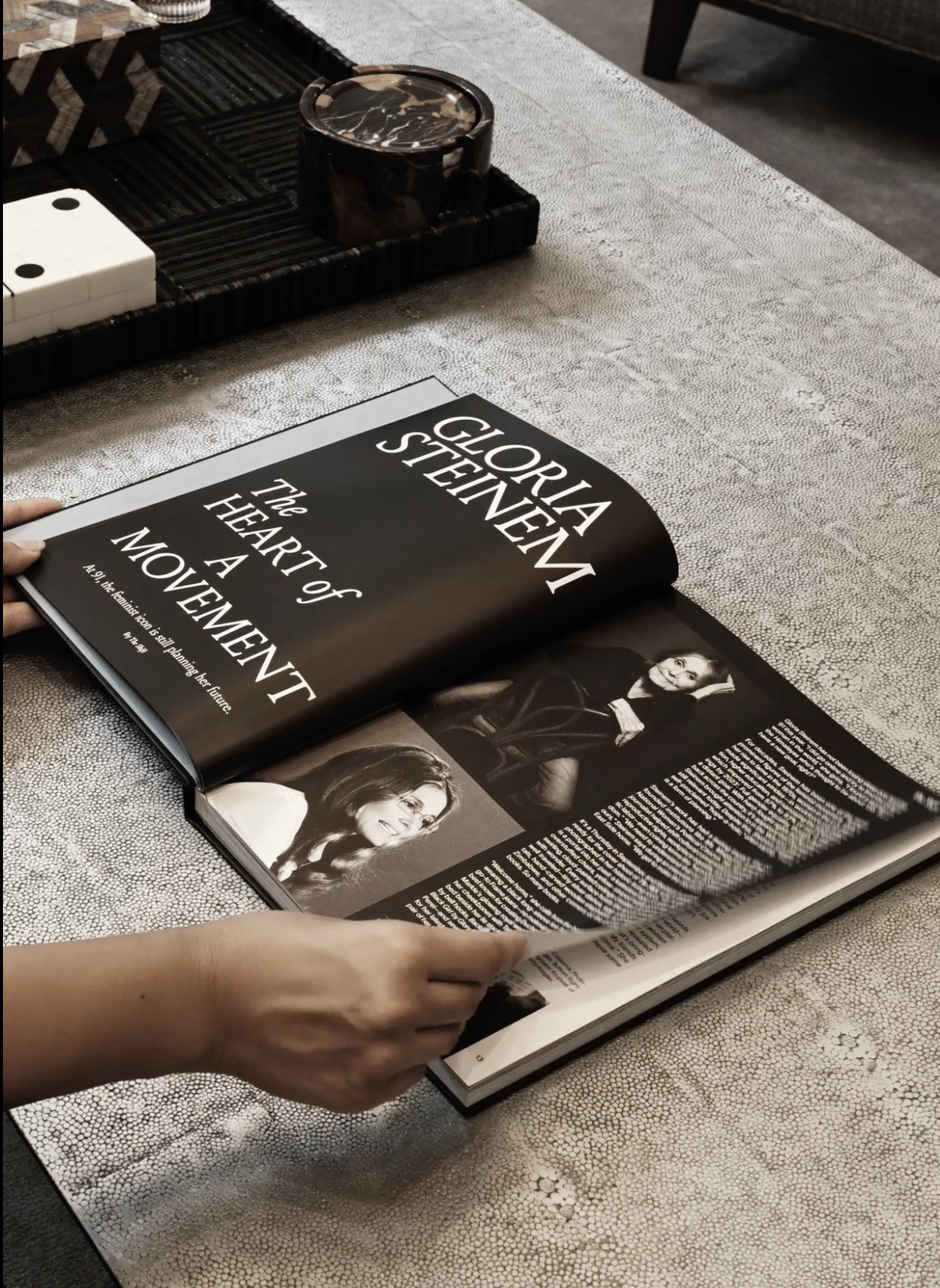 Open magazine with article about Gloria Steinem titled "The Heart of a Movement" on a textured table. The magazine features black and white photographs of Gloria Steinem.