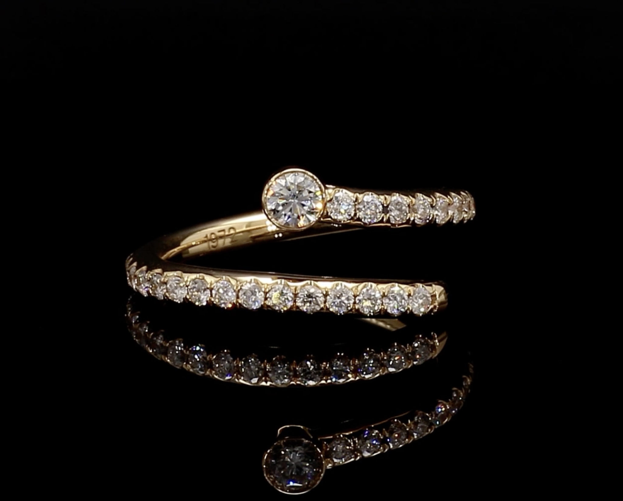 A gold ring with a large center diamond and smaller diamonds along the band, set against a black background.