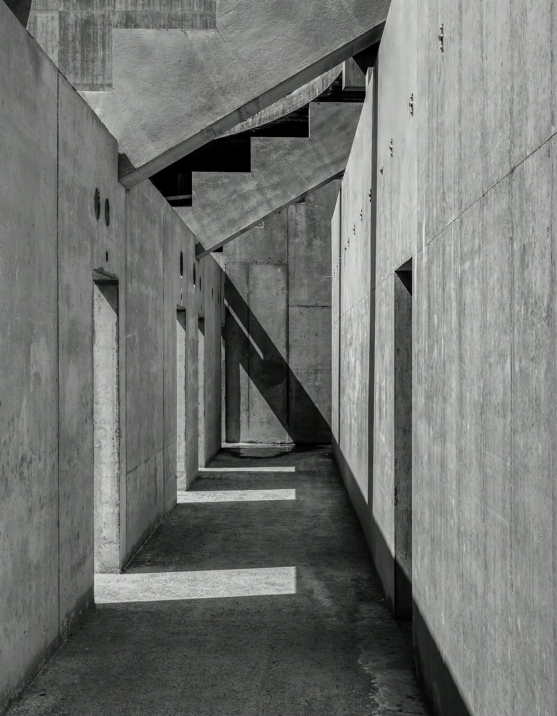 Black and white photo of concrete building exterior with shadow patterns on ground