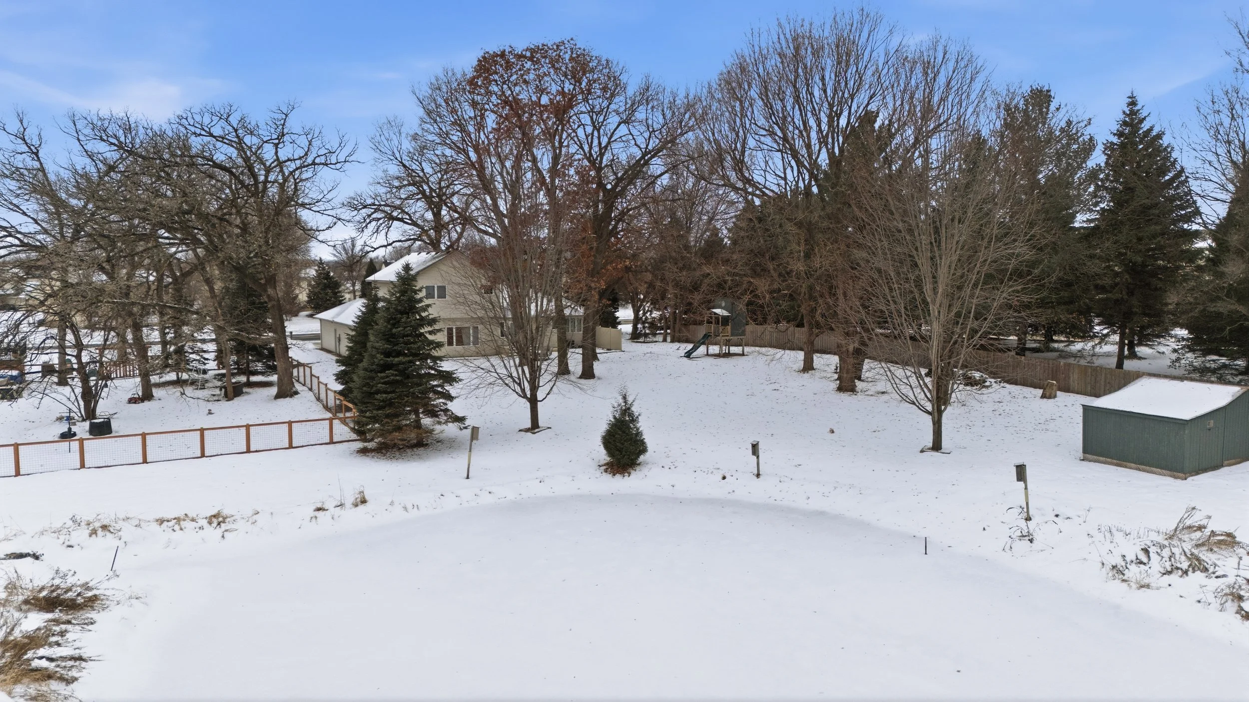 Drone photo of a backyard and neighboring homes covered in snow with a backyard pond in Chanhassen, Minnesota.