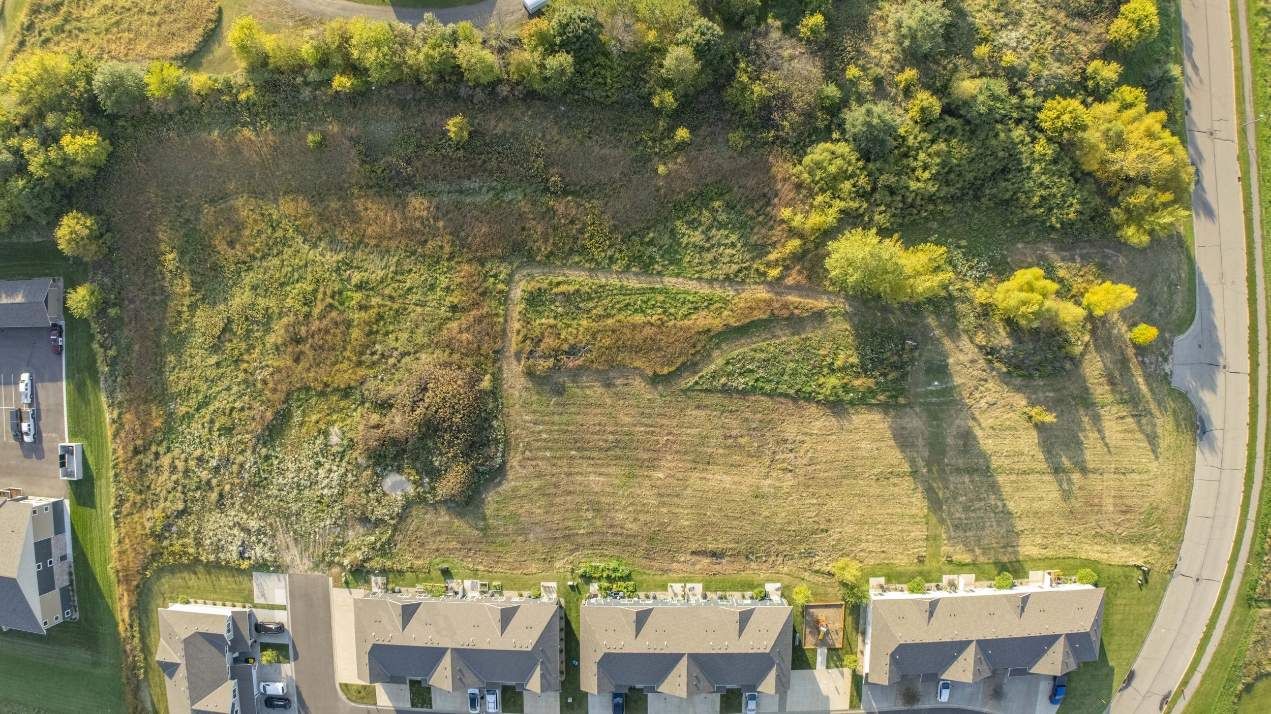 Top-down drone image showing a vacant residential lot and neighboring townhomes in the Twin Cities.