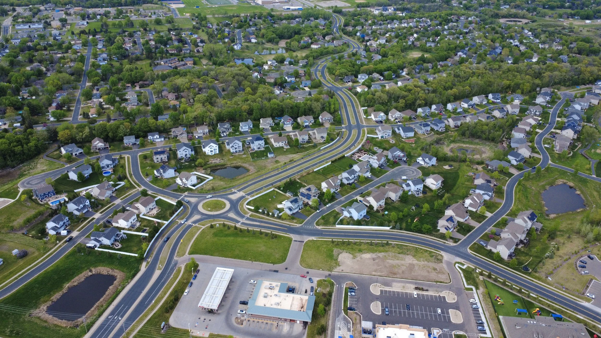 Aerial view of a suburban neighborhood nearby commercial land with curved roads and homes in the Twin Cities area.