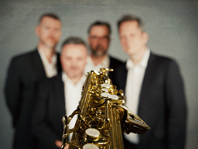 a floating saxophone and 4 blurry males behind it