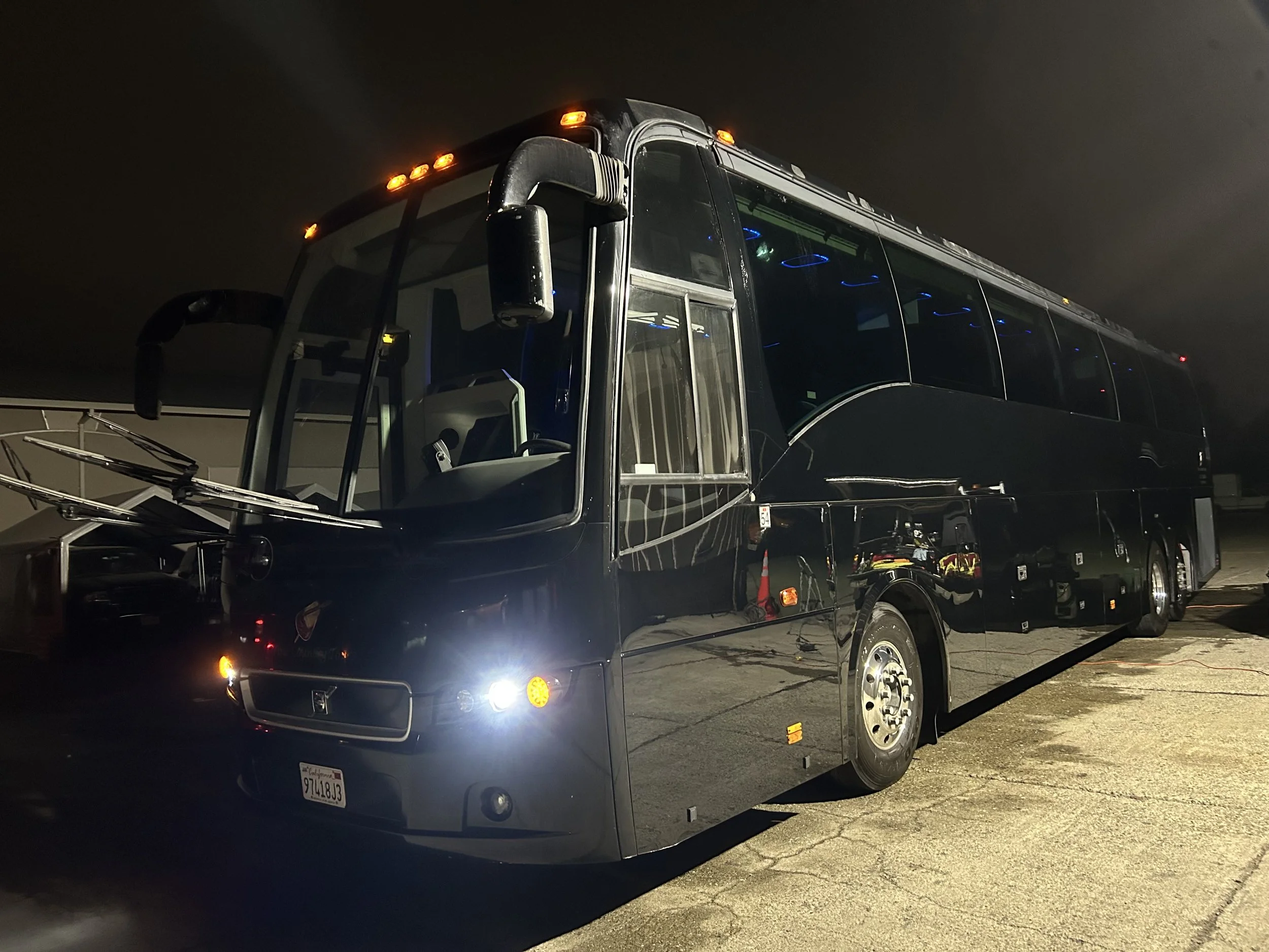 Sunrise over a frozen lake with rocks and trees, snow-covered mountains in the background, and a small island with trees in the middle of the lake.