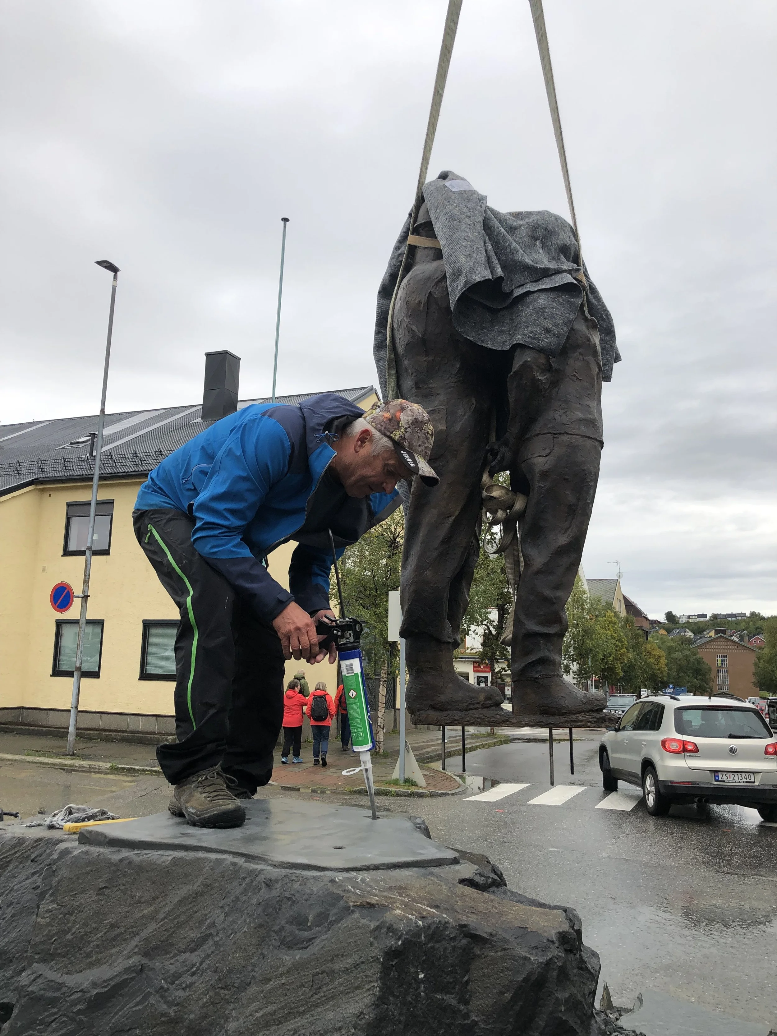 En liten betongsåle er støpt for at figurene skal stå i vater. Halle Mikkelborg legger på lim i hullene som boltene skal inn i.