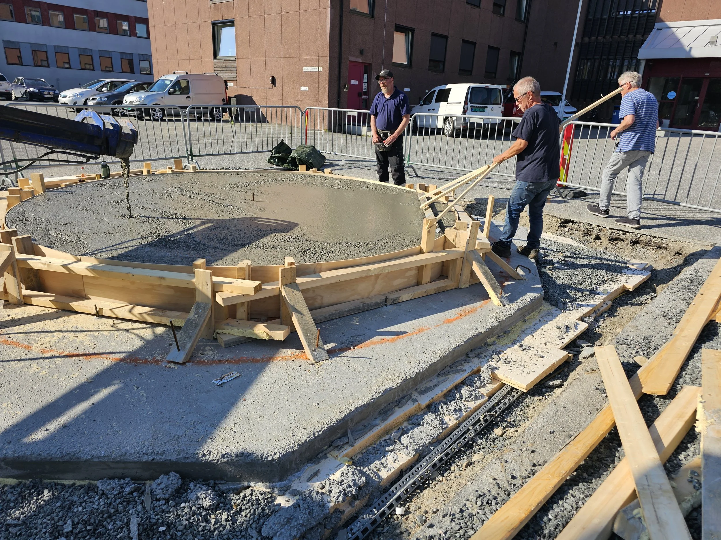 Betongen fylles i fundamentet. Charles Mortensen og Trond Hansen og operatøren fra betongbilen.