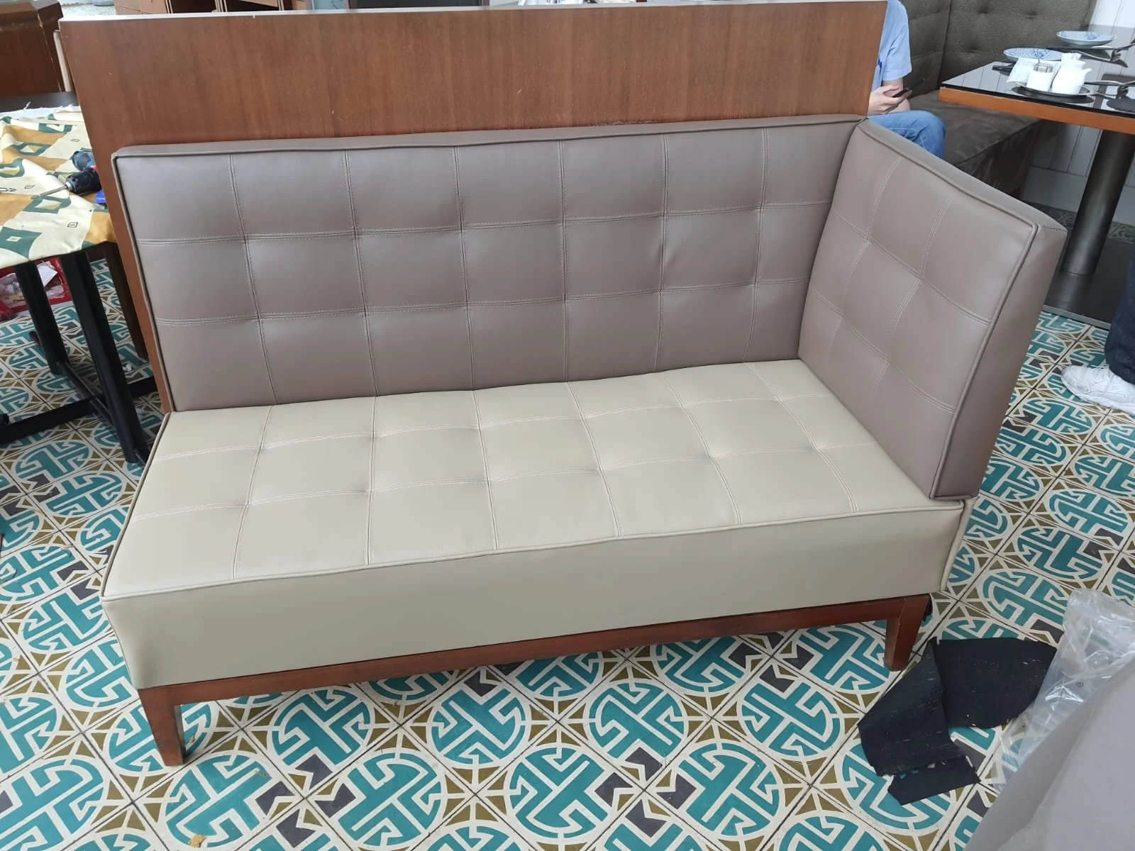 A vintage two-tone wooden and vinyl corner bench with beige and taupe cushions inside a restaurant or cafe.
