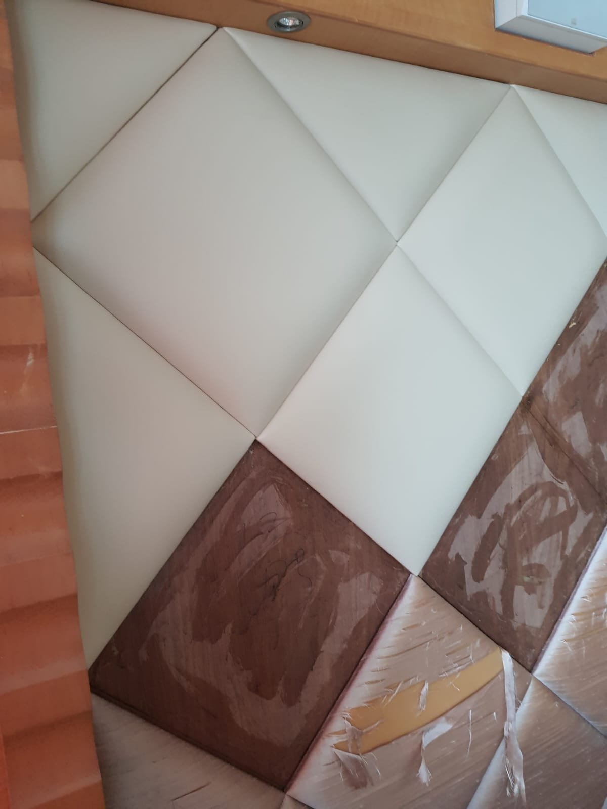 A collection of upholstered cushions arranged in a geometric pattern on a wooden floor, with some cushions showing signs of damage or wear.