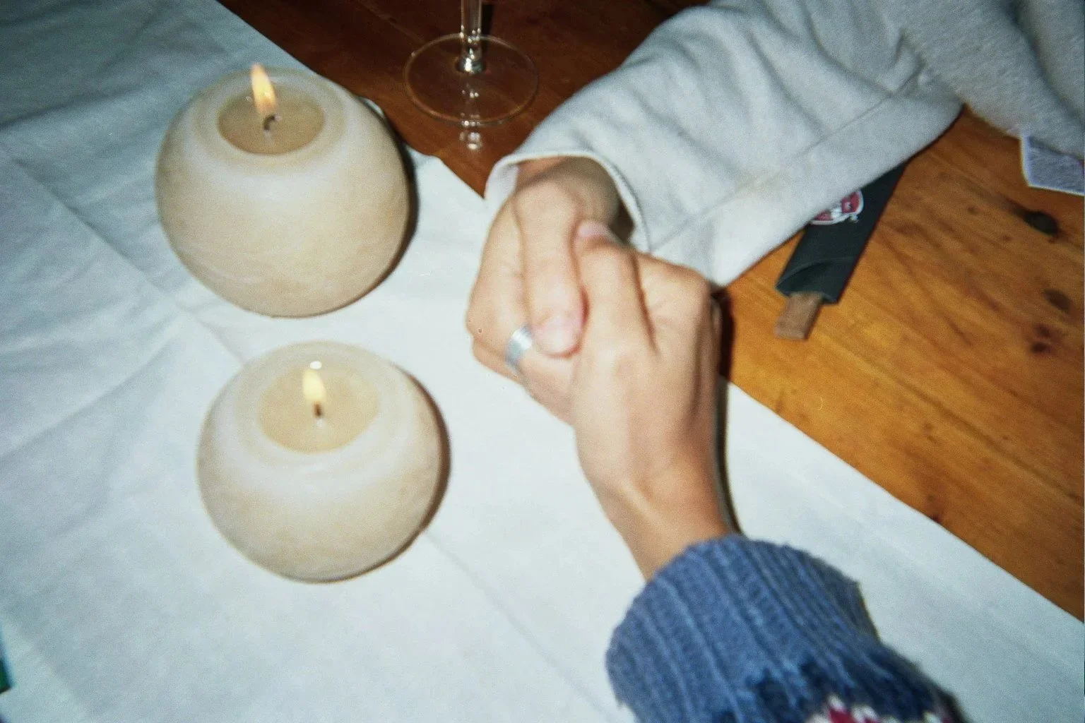 Persona purificando sus manos con gel hidroalcohólico en una mesa con velas y una copa de vino.