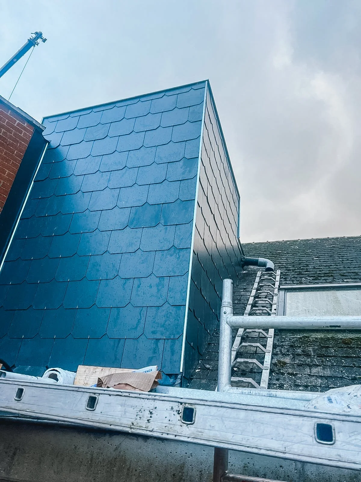 Bouwplatform met een huis dat van nieuwe blauwe dakpannen is voorzien.