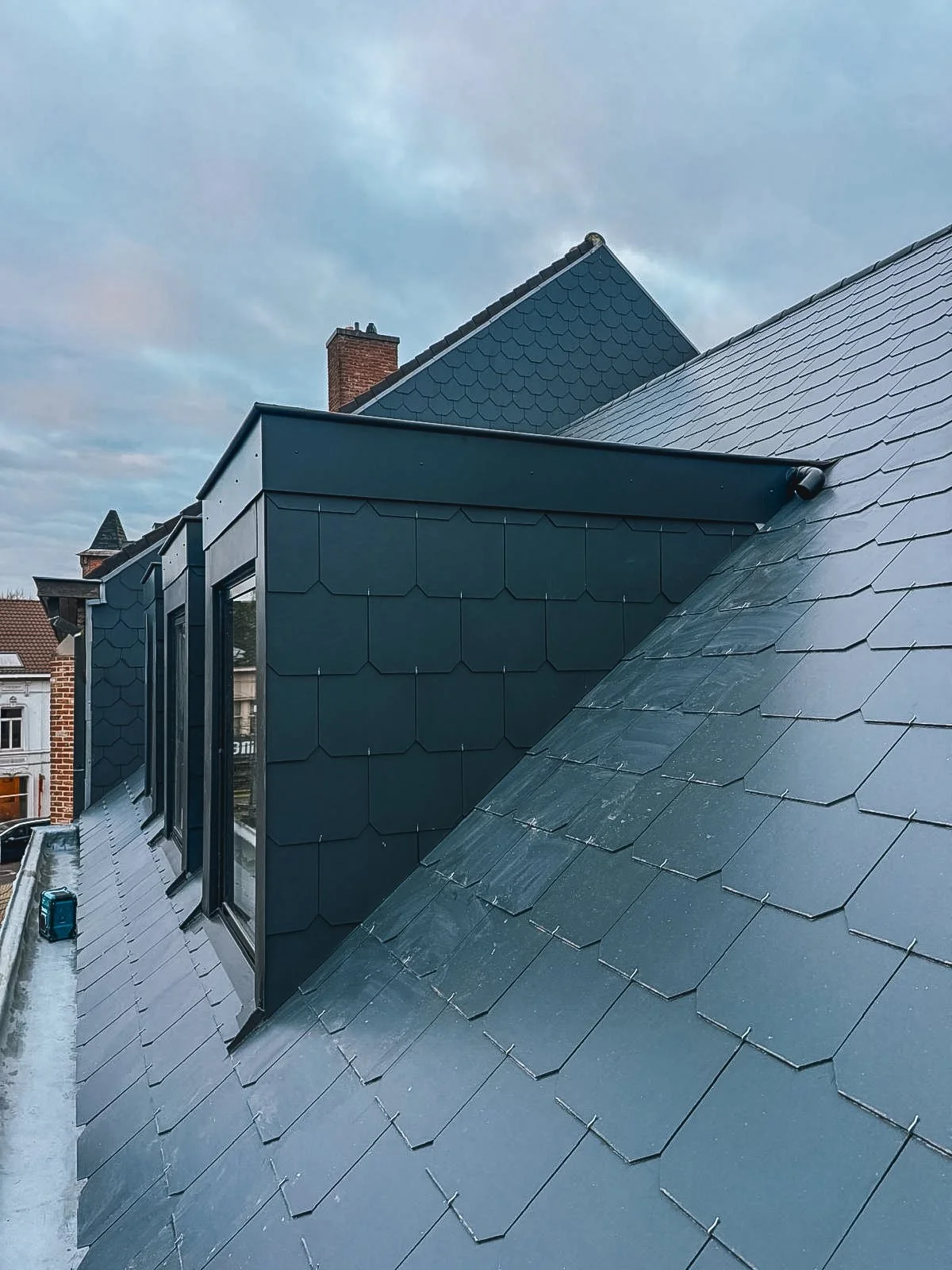 Moderne dakbedekking met metalen en dakpannen op een gebouw onder een bewolkte sky.