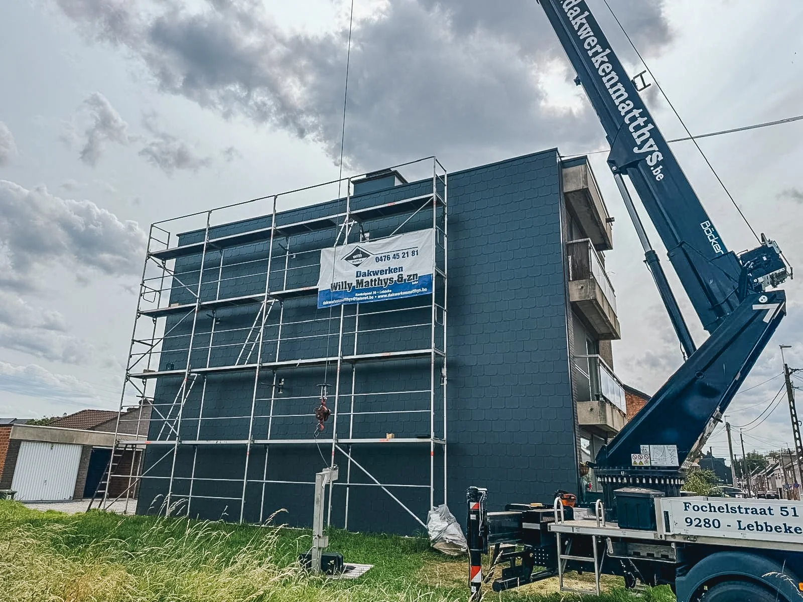 Een bouwplaats met een gebouw dat wordt geschilderd of gerepareerd, omgeven door steigers en een hijskraan.