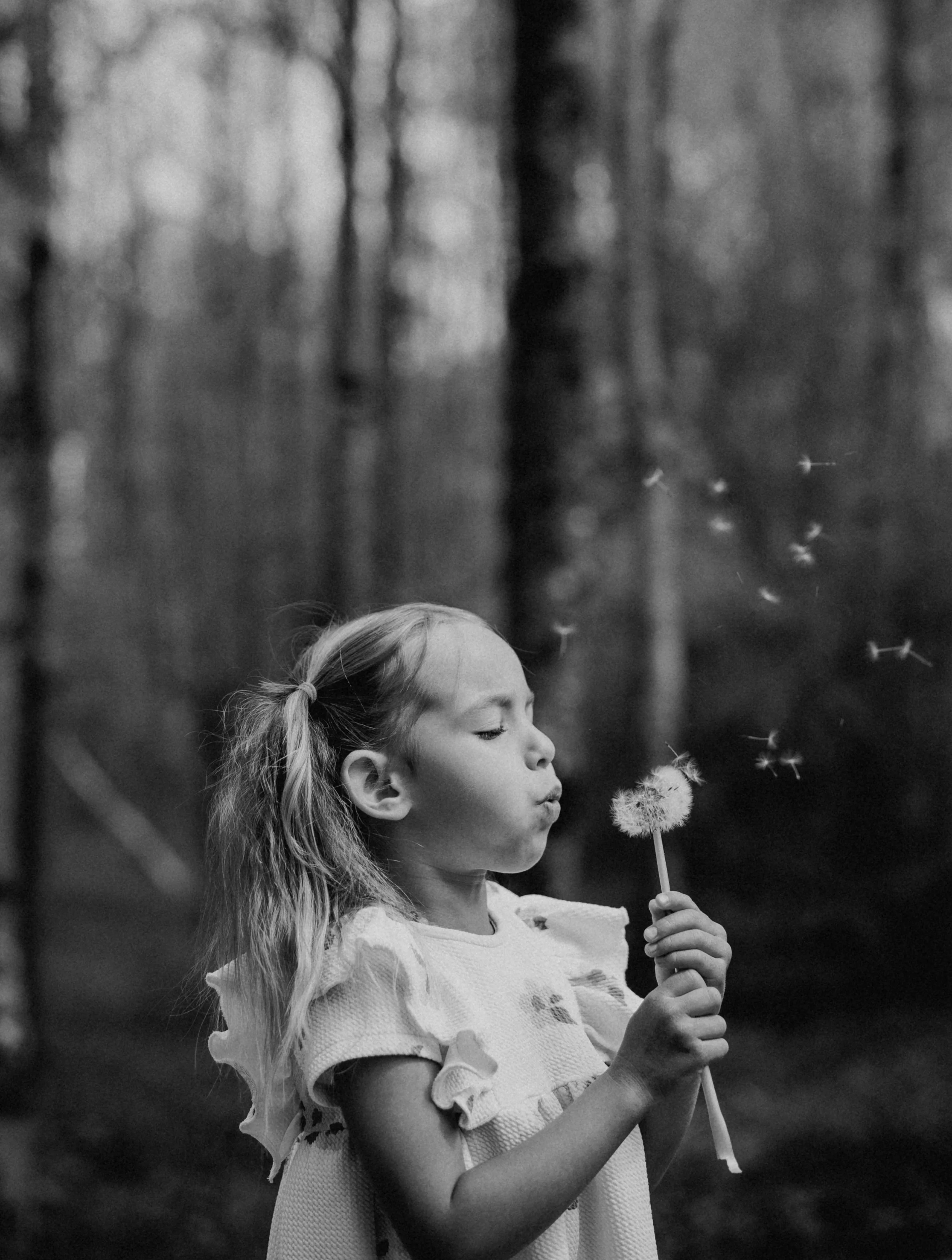 Mädchen pustet eine Pusteblume
