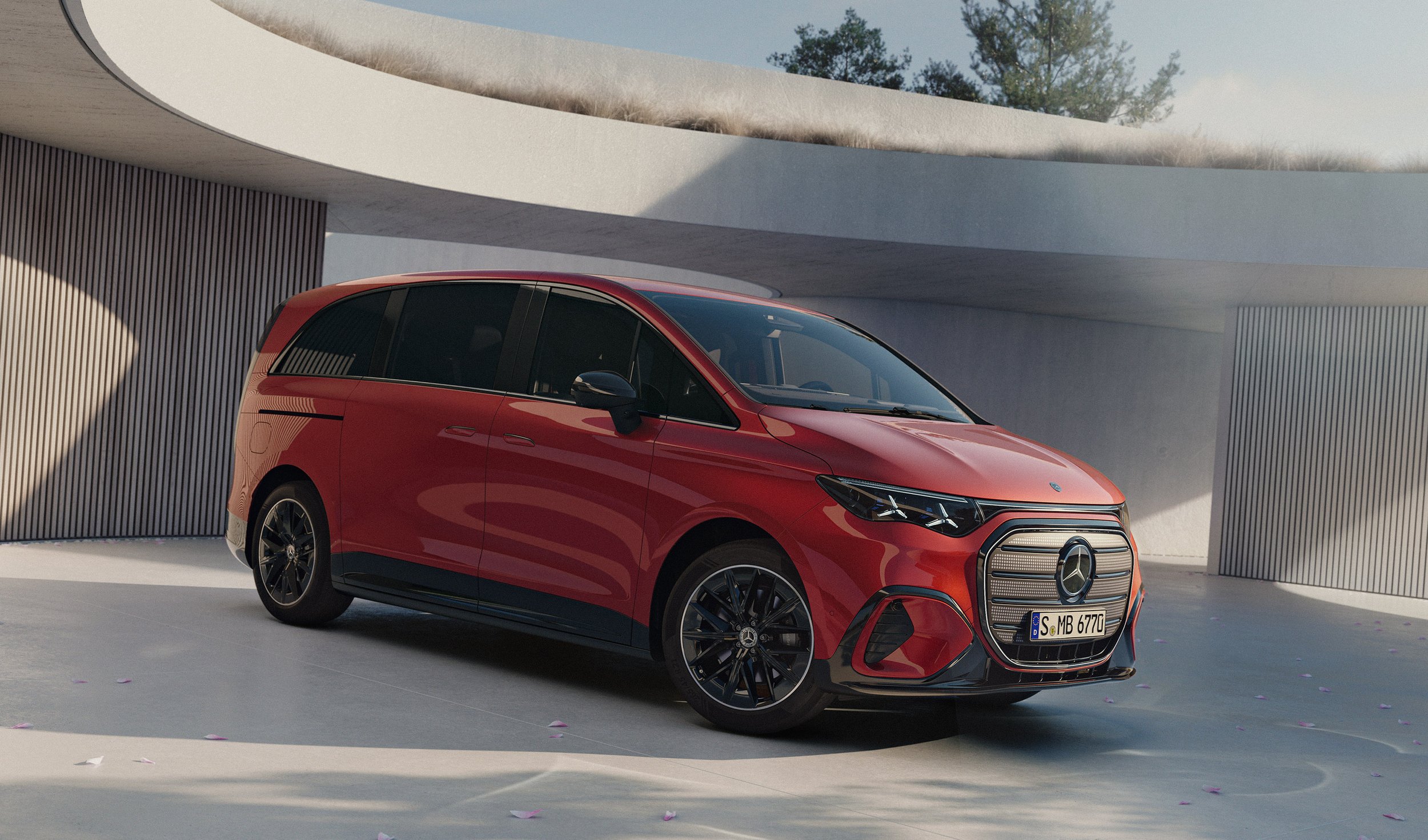 Ein rotes Mercedes-Benz Auto auf einer modernen, minimalistischen Hofausstellung mit weißen Wänden und geschwungenen Deckenbögen. Der Himmel ist blau, und im Hintergrund sind Bäume zu sehen.