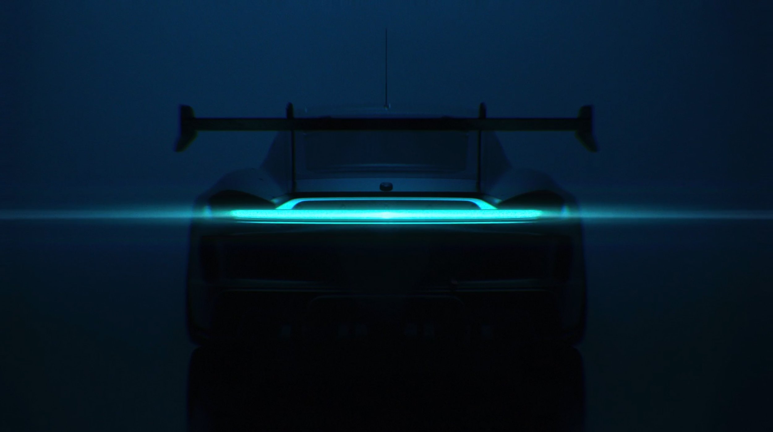 Ein futuristisches Rennauto auf einer dunklen, nebligen Oberfläche, mit blauen Neonlichtern akzentuiert.
