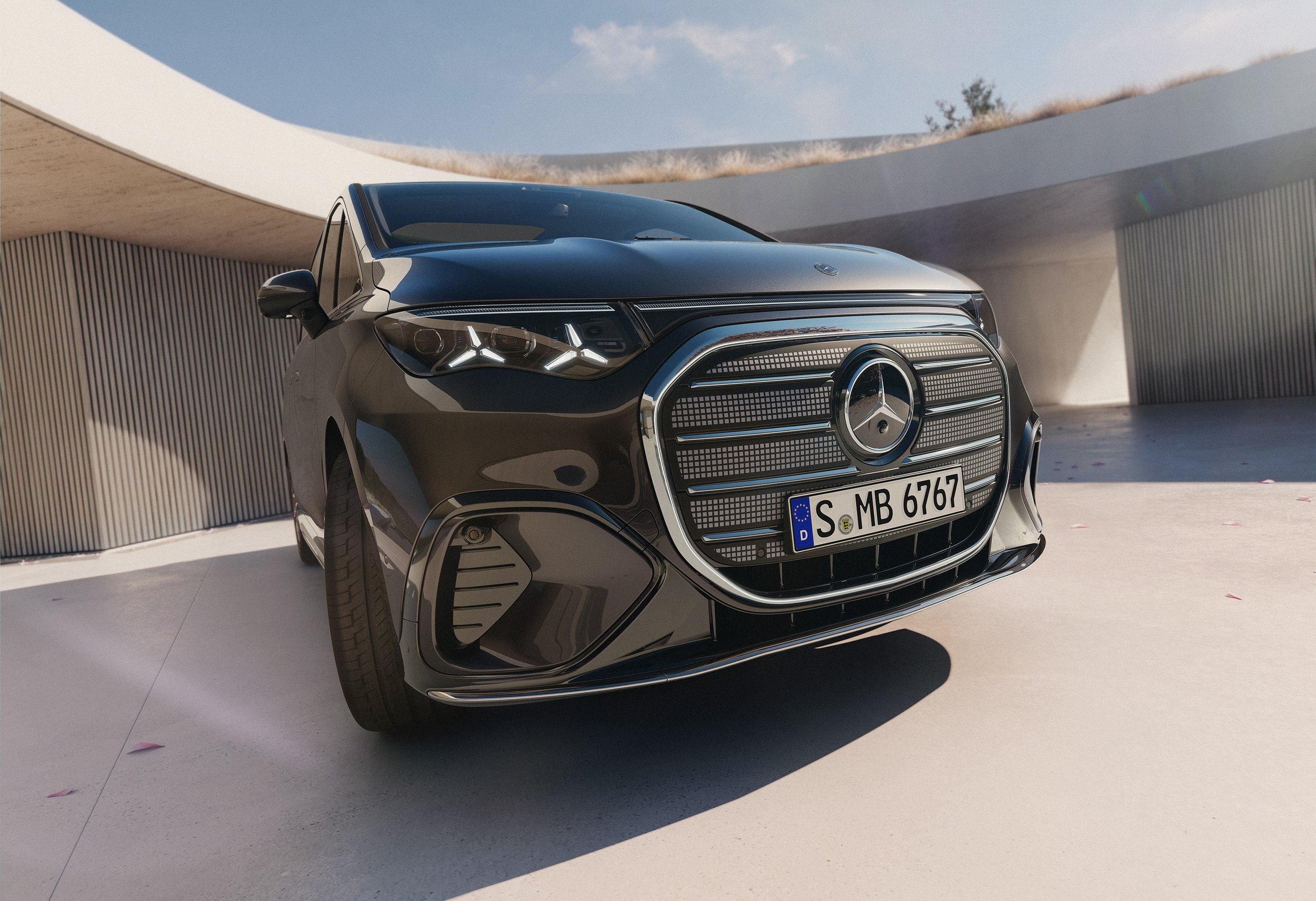 Ein schwarzer Mercedes-Benz elektrischer SUV mit modernem Grill und deutschem Kennzeichen, geparkt vor einem modernen Gebäude mit asymmetrischem Dach und Holzverkleidungen.