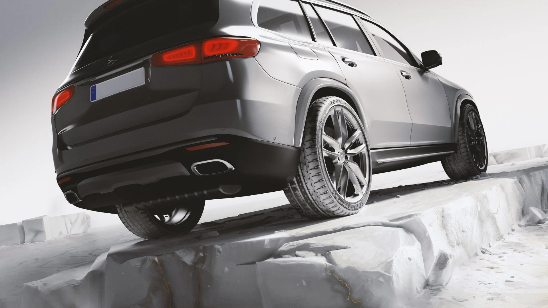 Ein grauer SUV fährt über schneebedecktes Gelände, Blick auf die Rückseite. Der Himmel ist bewölkt, und die Reifen sind speziell für winterliche Bedingungen ausgelegt.