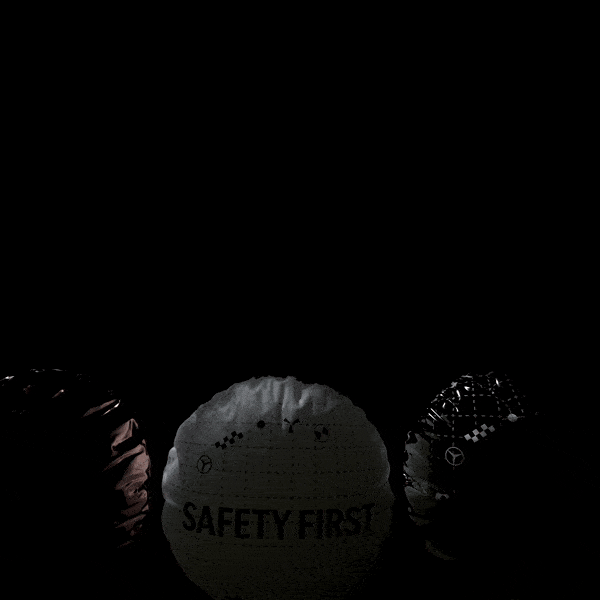 Drei zusammengeknotete Sicherheits- oder Heliumballons in Schwarz, Weiß und Rot, mit sichtbarem Text "SAFETY FIRST" auf dem weißen Ballon, vor dunklem Hintergrund.