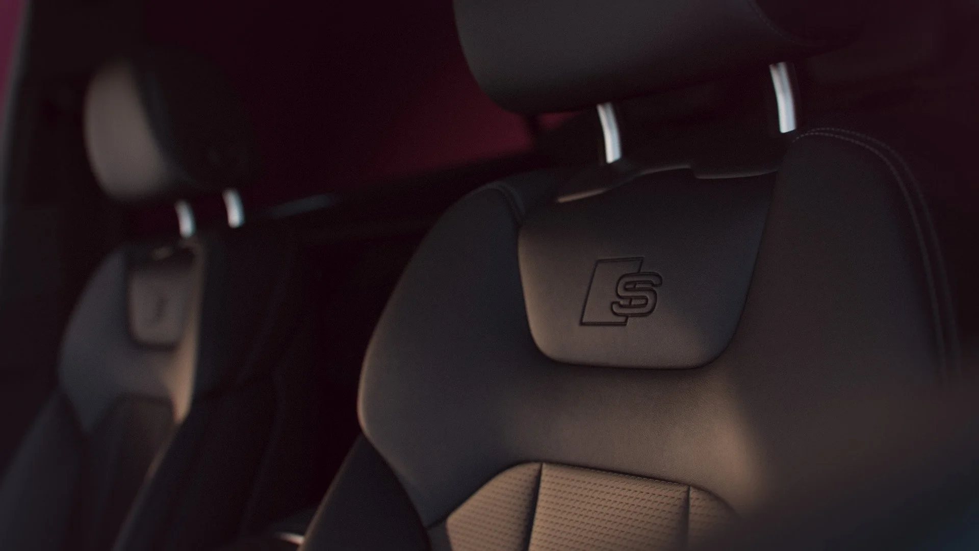 Innenraum eines Autos, Blick auf die Rücksitze und das Logo Audi auf einem Sitzkissen.