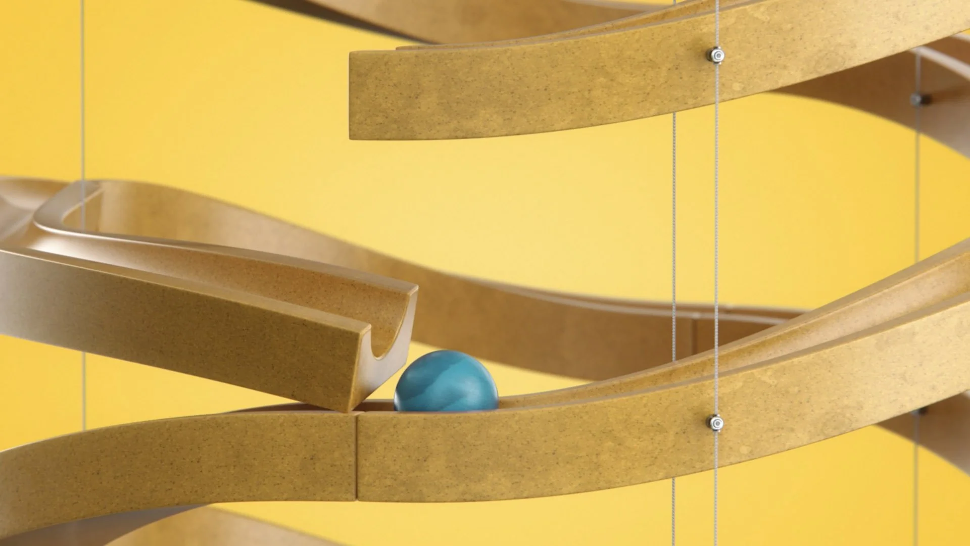Ein kinetisches Basisset mit einer blauen Kugel auf einer spiralförmigen Bahn, gelben und braunen Teilen, an einer Wand montiert.