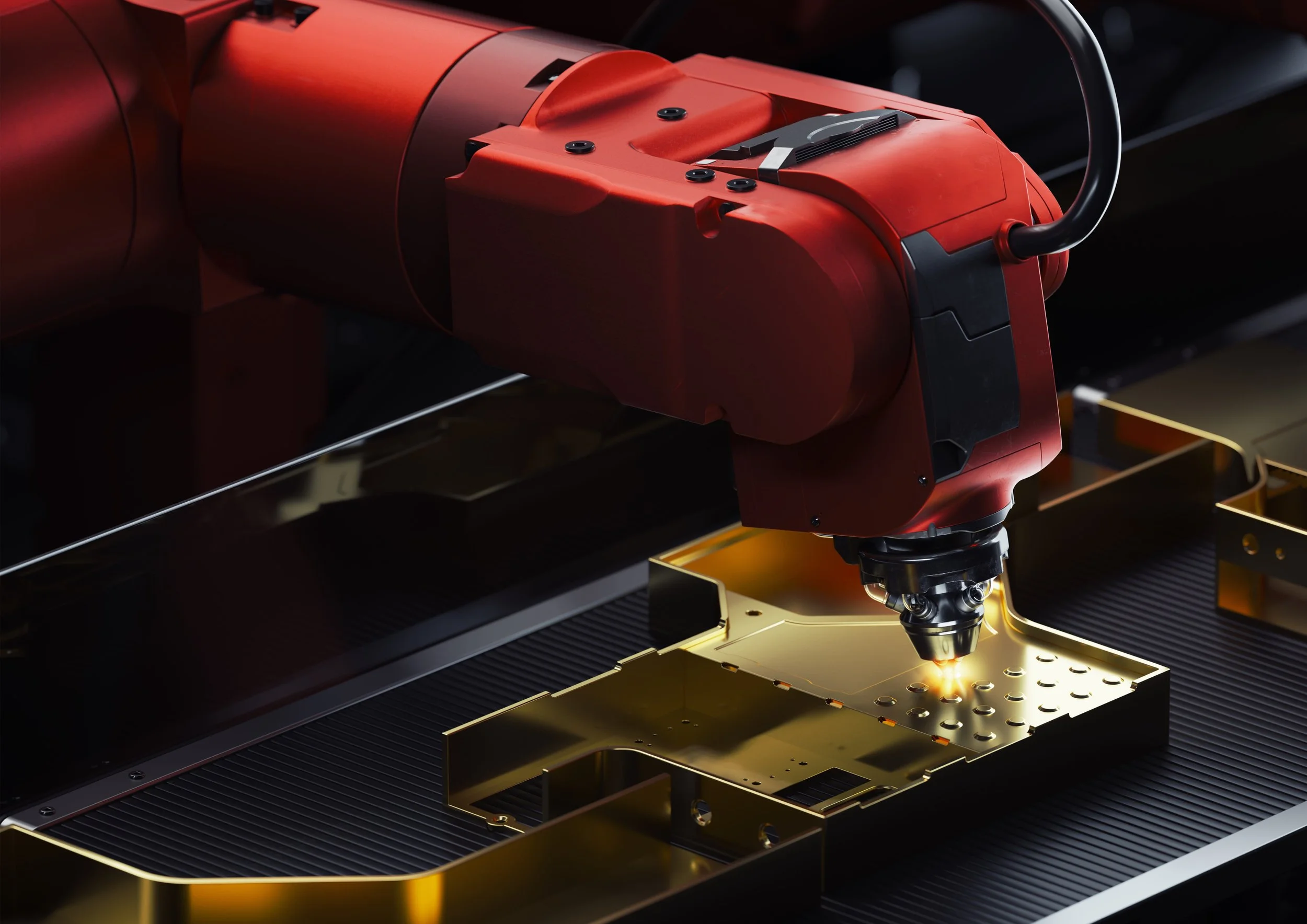 Ein präzises Gerät mit rotem Gehäuse, das in einer Maschine arbeitet, um eine goldene Metallplatte mit mehreren Löchern zu bearbeiten.