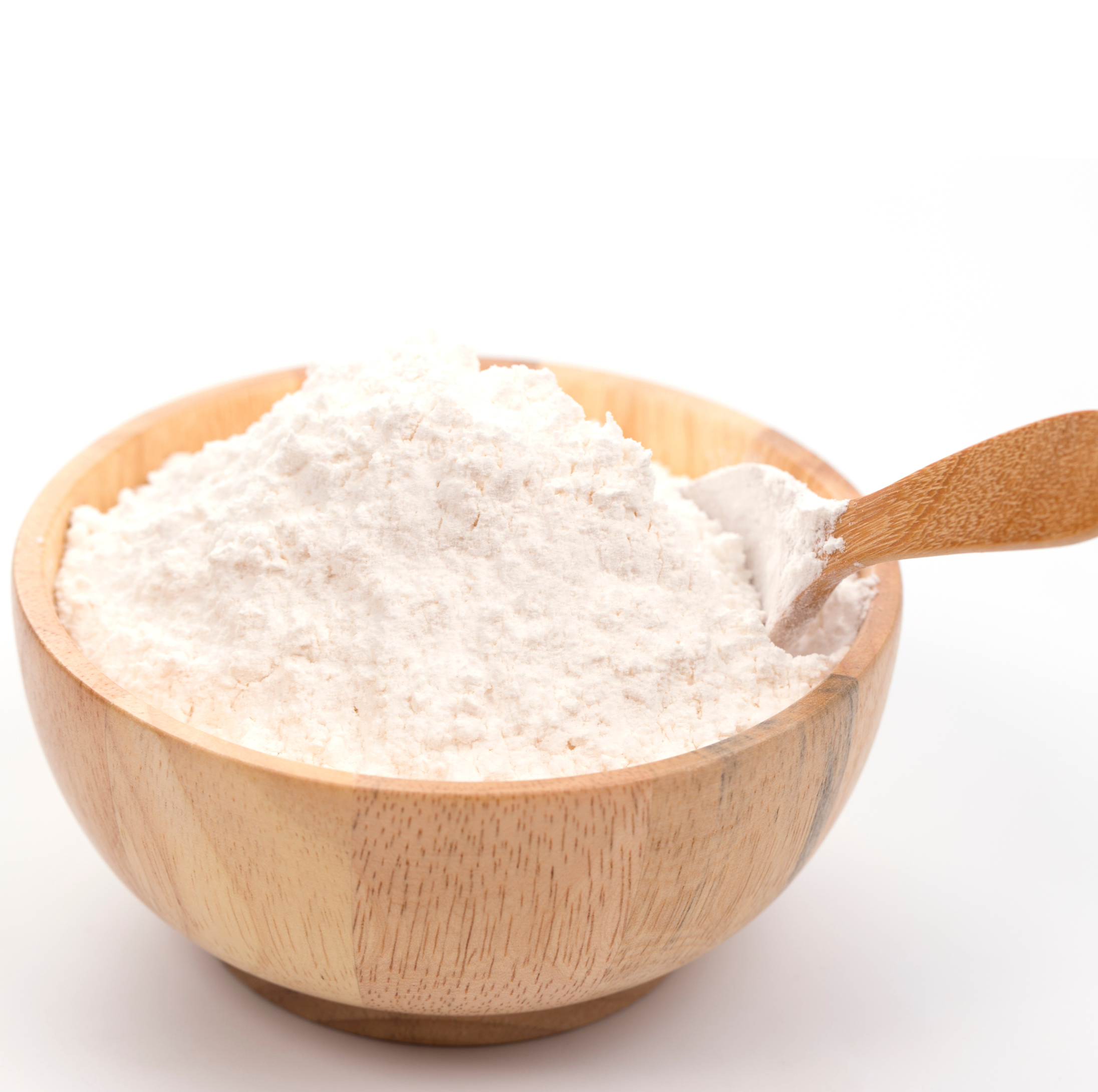 Wooden bowl filled with white flour and a wooden spoon resting inside