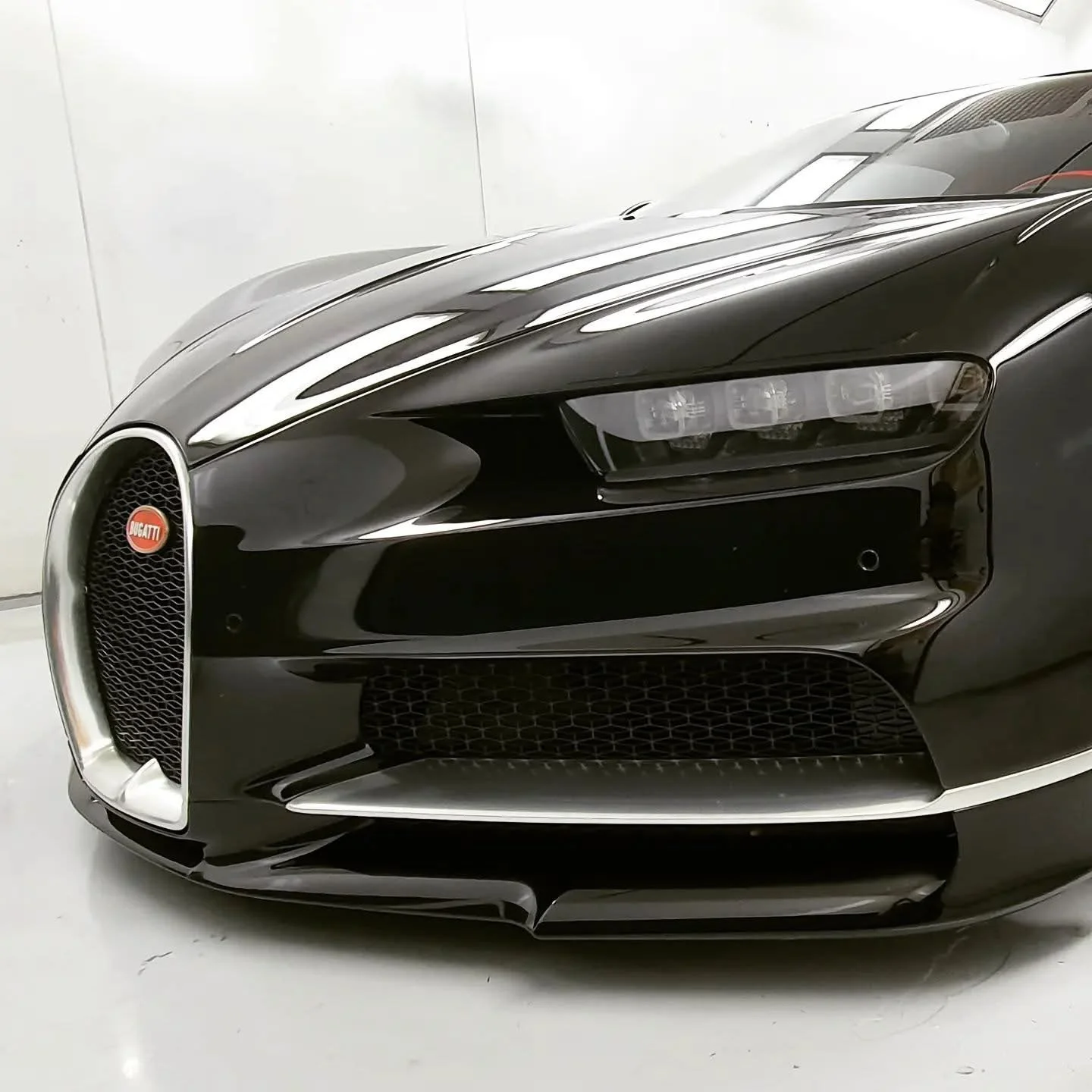 Close-up of a black Bugatti sports car's front with distinctive grille and sleek design in a garage.