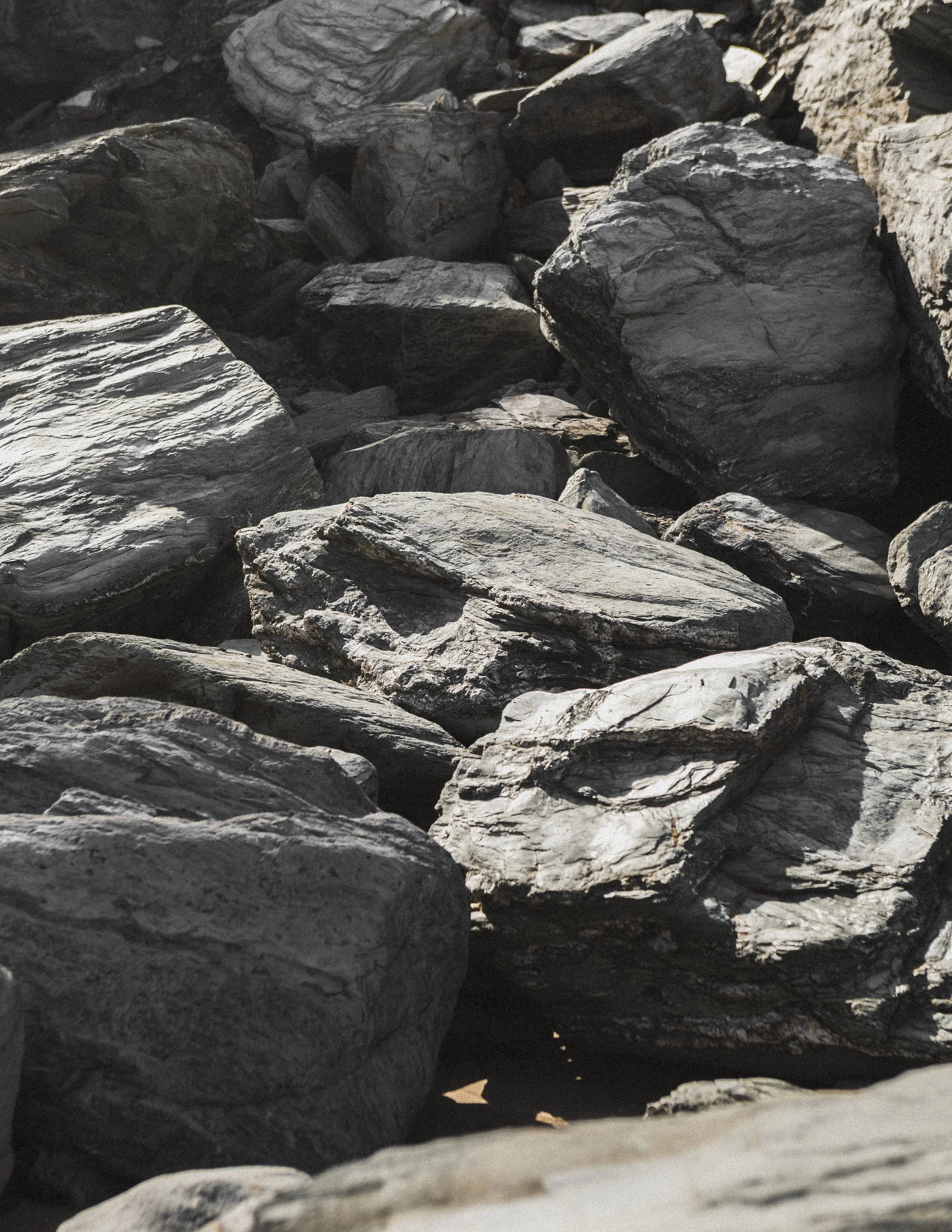 Close-up view of large dark gray rocks and stones on a beach.