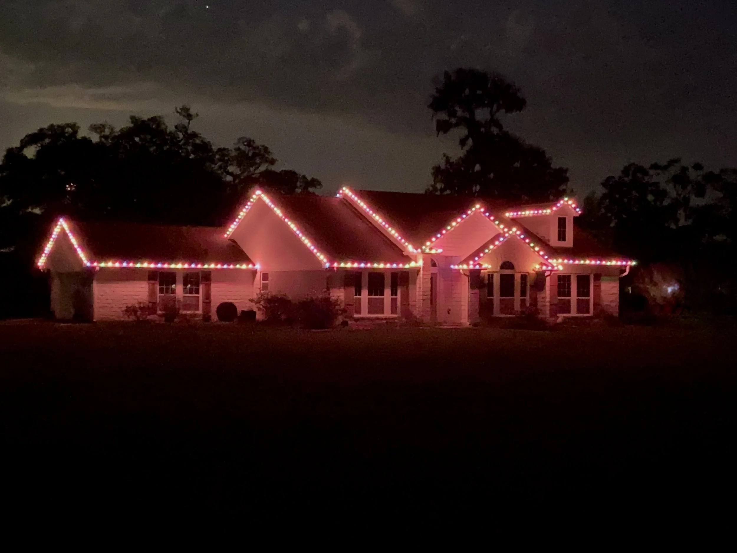A house decorated with colorful Christmas lights at night.