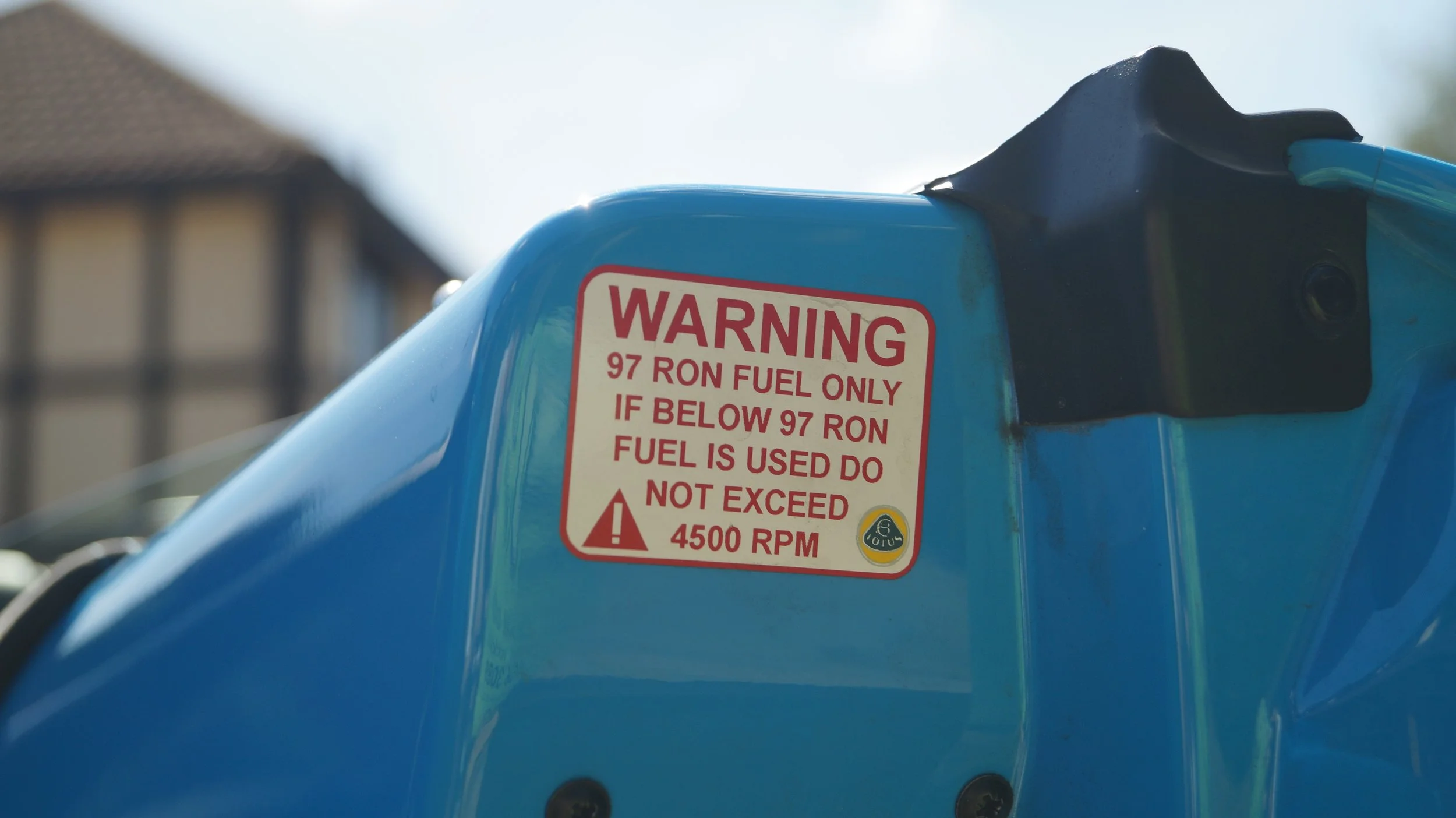 Close-up of a Lotus with a warning label about fuel and RPM limits.