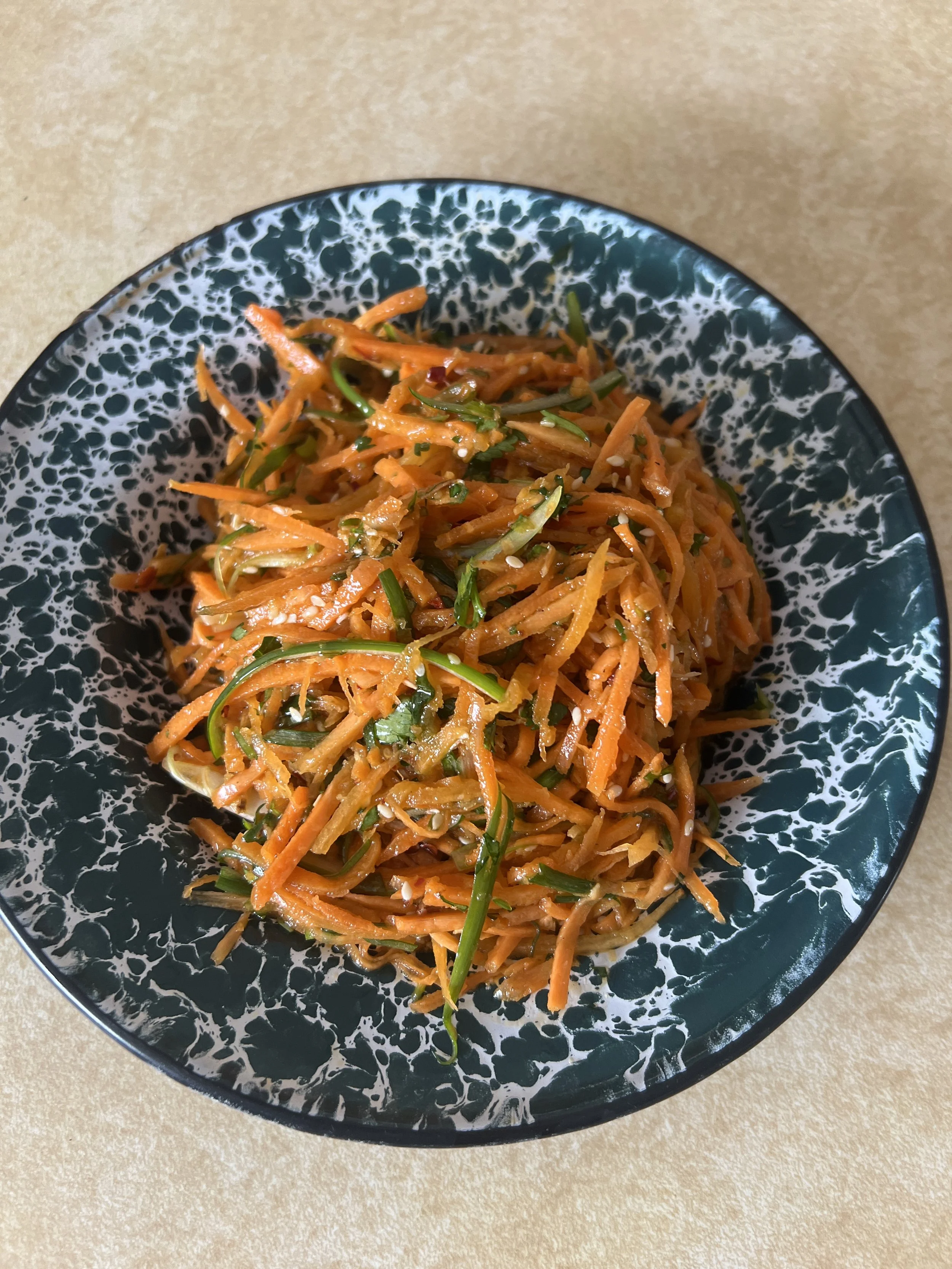 Asian-inspired carrot salad with green onions and seasame seeds on a plate